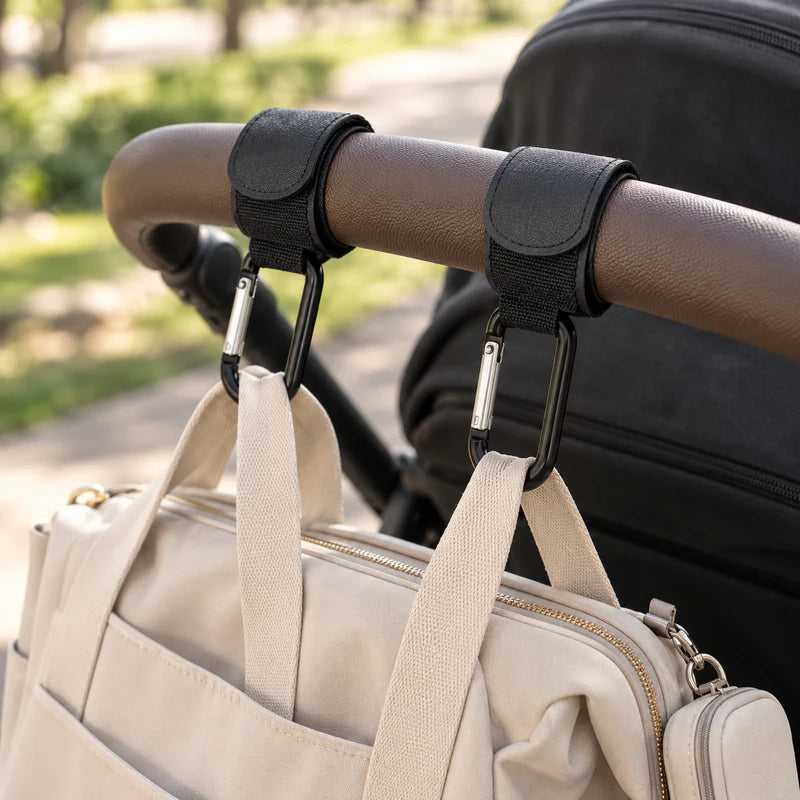 Deux attaches poussette noires fixées sur la barre d'une poussette avec un sac à langer accroché