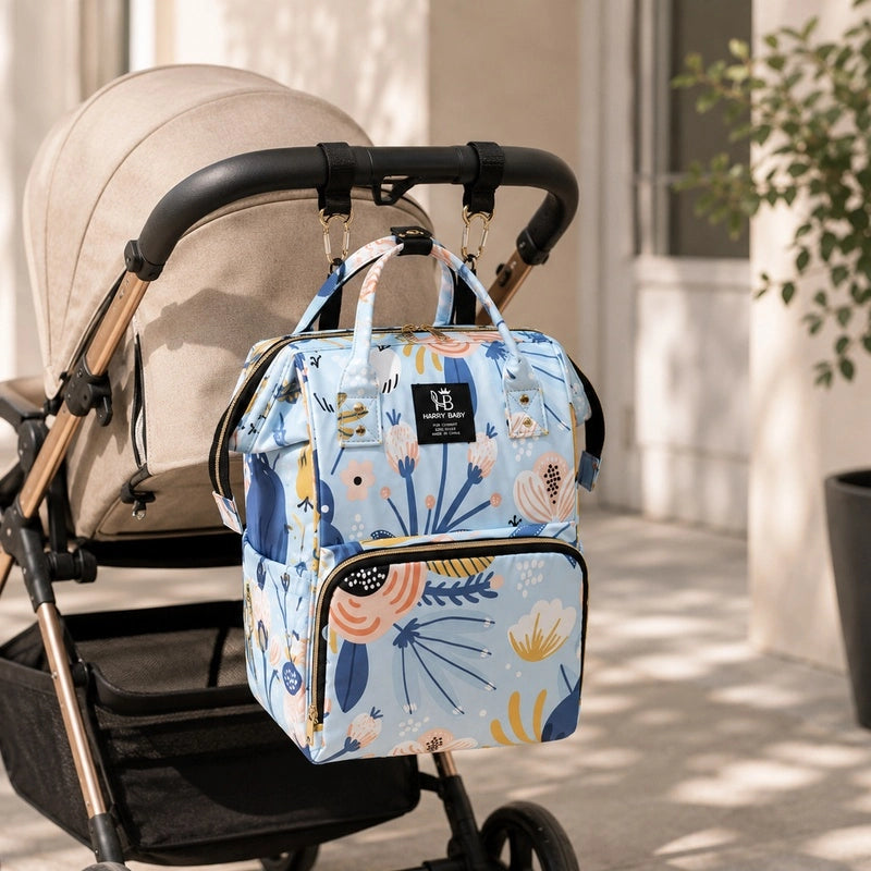 Sac à dos à langer bébé bleu fleuri accroché aux poignées d'une poussette