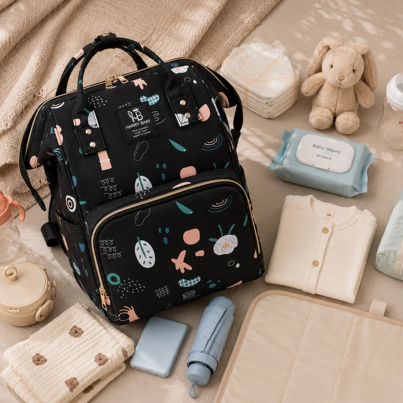 Sac à dos à langer bébé Harry Baby noir entouré d'accessoires de puériculture