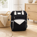 Sac à dos à langer noir posé au sol dans une chambre bébé, vue de face