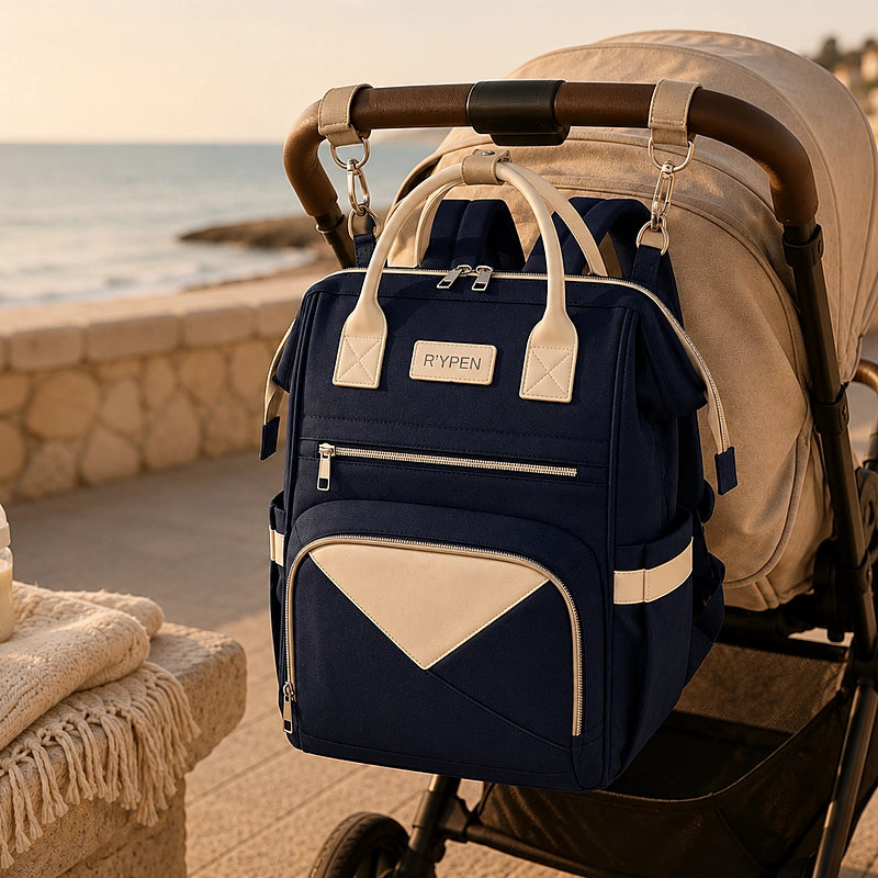 Sac à dos à langer bleu marine accroché à la poignée d'une poussette au bord de mer