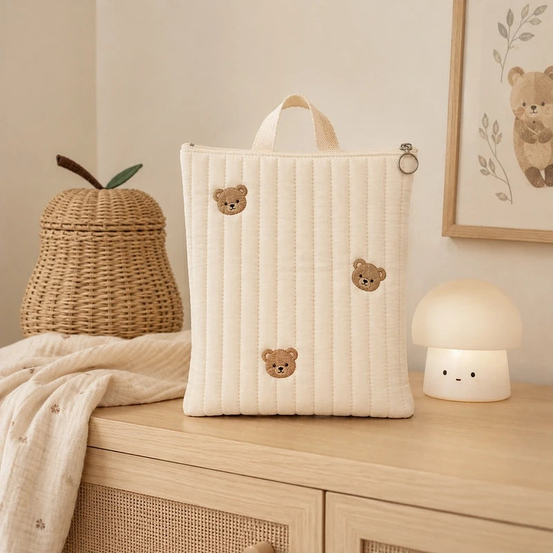 Pochette couche bébé écru, broderie têtes d'ours, posée sur un meuble