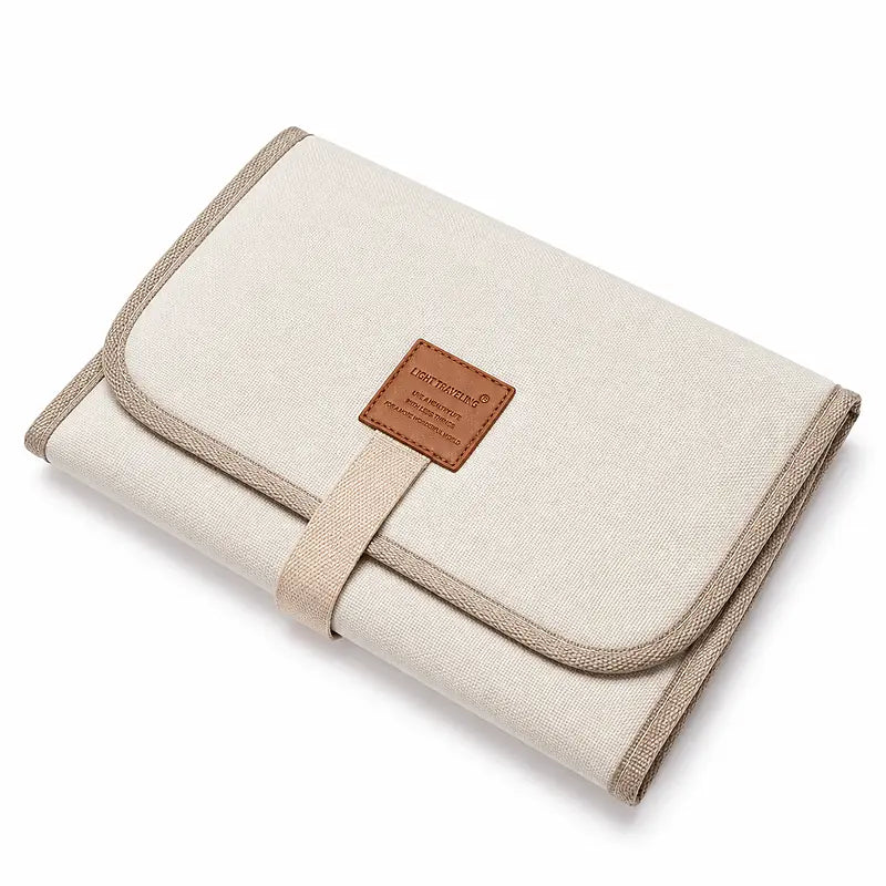 Tapis de change bébé nomade plié blanc crème avec sangle de fermeture, format compact voyage
