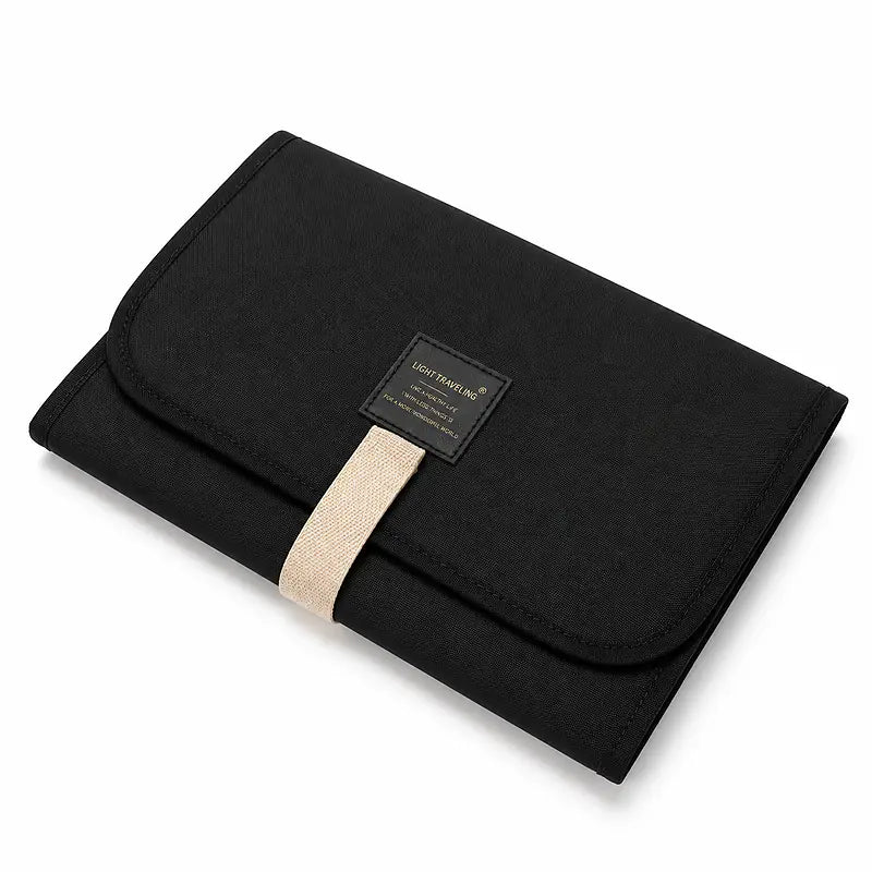 Tapis de change bébé nomade plié noir avec sangle beige et liseré, format compact voyage