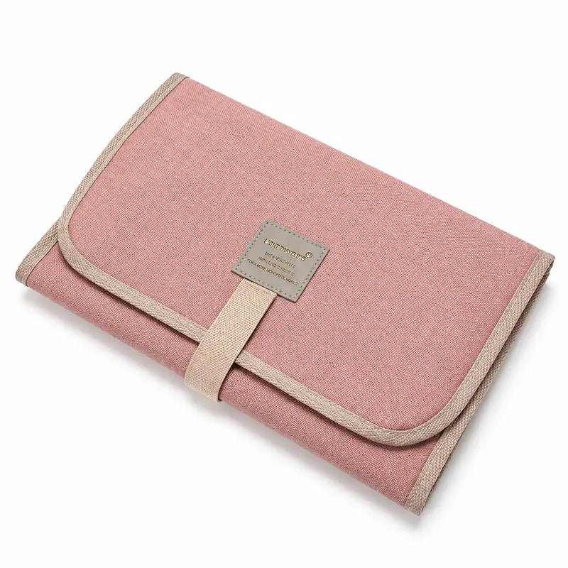 Tapis de change bébé nomade plié rose avec sangle de fermeture, format compact voyage